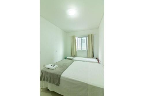 een witte slaapkamer met een bed en een raam bij Supremo in Meia Praia