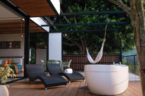 a patio with chairs and a bath tub on a deck at Hotel Casa Ambrosia in Villeta