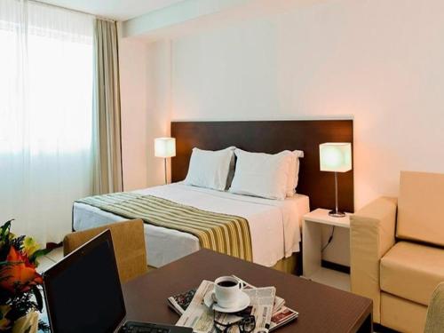 a hotel room with a bed and a desk with a laptop at Pacific Flat da Miramar in Tambaú