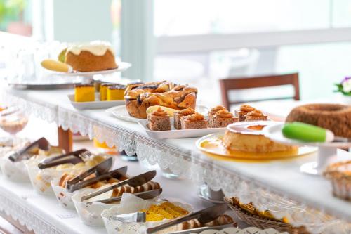 einen Tisch mit verschiedenen Arten von Gebäck und Kuchen in der Unterkunft Pousada Pérola de Ubatuba in Ubatuba