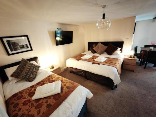 a hotel room with two beds and a dining room at Dolgun Uchaf Guesthouse and Cottages in Snowdonia in Dolgellau