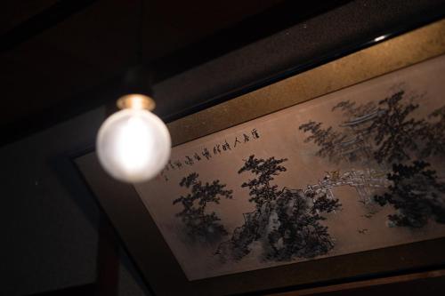 a light hanging from a wall with a picture at 蔵サウナのある貸切古民家宿 ojirotomarlo in Tsuiyama