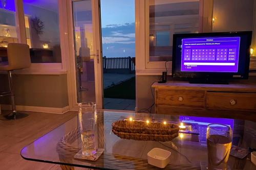 a living room with a table with candles and a television at BRiSYL BEACH HOUSE, with amazing changing views! in Kent