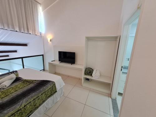 een slaapkamer met een bed en een flatscreen-tv bij Laguna Beach Porto de Galinhas in Camela