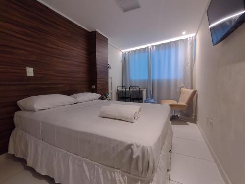 een slaapkamer met een groot wit bed met een houten hoofdeinde bij Manaíra Palace Residence in João Pessoa