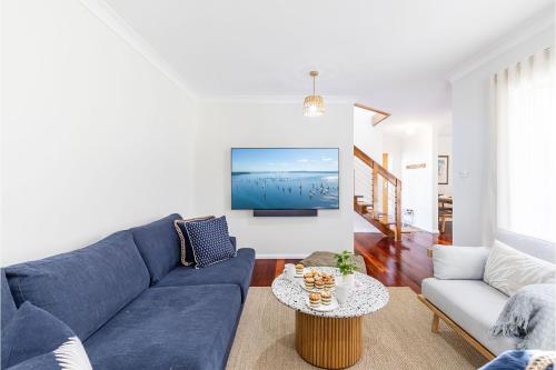 a living room with a blue couch and a table at Banksia at Fingal 1 92 Rocky Point Rd Aircon spa and Wi Fi in Fingal Bay