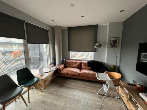 a living room with a brown leather couch and chairs at East London's hidden gem - relax after sightseeing in a huge canal view balcony in London