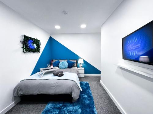 a bedroom with a blue accent wall and a large tv at Cosy Contemporary Apartment - Brimsdown, Enfield in Enfield Lock