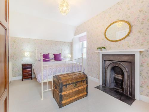 a bedroom with a bed with a fireplace and a mirror at Colaboll Farmhouse in Lairg