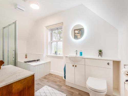 a white bathroom with a sink and a mirror at Colaboll Farmhouse in Lairg