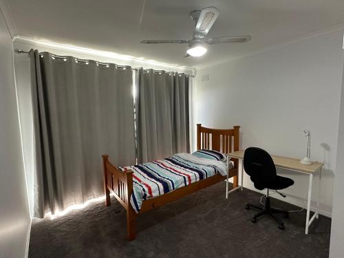 a bedroom with a bed and a desk and a window at Comfy bed quiet neighbourhood in Grovedale