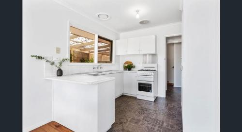 a white kitchen with a sink and a stove at Comfy bed quiet neighbourhood in Grovedale