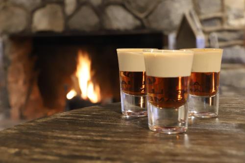 two glasses of beer sitting on a table in front of a fireplace at Ski Rider Hotel in Kalkite