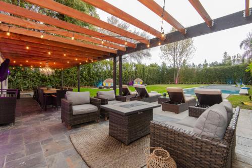 an outdoor patio with chairs and tables and a pergola at Woodland Hills Paradise Resort Style Home in Los Angeles