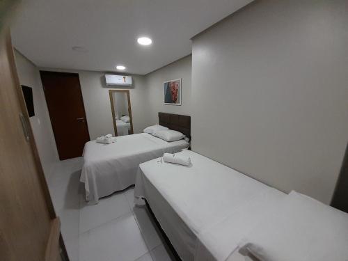 Habitación hospitalaria con 2 camas y espejo en Lindo Apartamento no Vuarnet, en João Pessoa