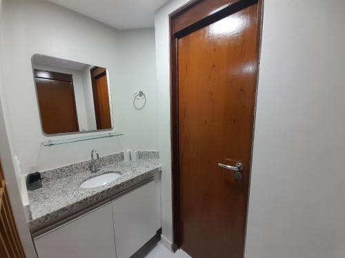 baño con lavabo y puerta de madera en Lindo Apartamento no Vuarnet, en João Pessoa