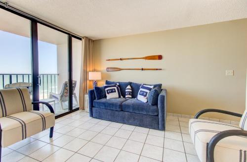 a living room with a blue couch and a balcony at 0610 Smooth Sailing by Atlantic Towers in Carolina Beach