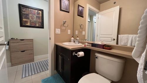 a bathroom with a toilet and a sink and a mirror at WATERSCAPES RESORT KELOWNA 2 FULL BEDROOMS SUITE VACATION RENTALS, SHORT TERM RENTALS. in Kelowna
