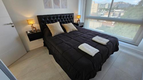 a black bed in a room with a large window at MaJo Apart in San Luis