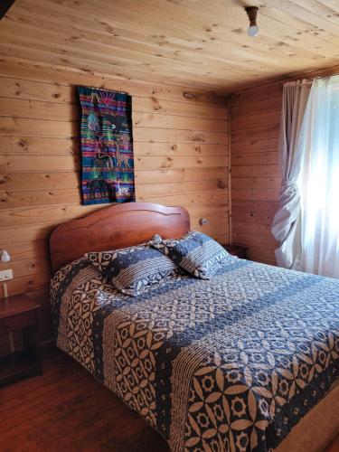 a bedroom with a bed in a log cabin at Cabañas Aguas Claras in Pinto