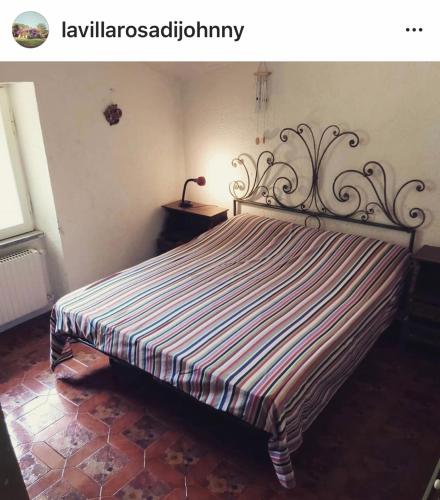 een bed in een slaapkamer met een gestreepte sprei bij La Villa Rosa di Johnny in Ronciglione