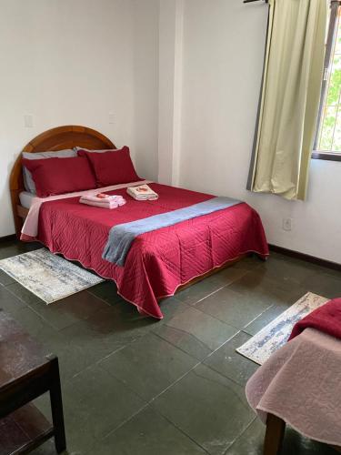 um quarto com uma cama com uma colcha vermelha em Casa em Itaipu em Niterói