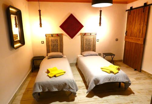 two beds in a room with yellow towels on them at Aladin Comfort Country T3 in Campinho