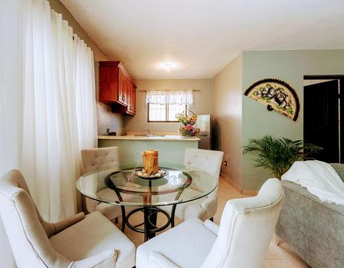 a dining room with a glass table and white chairs at Como en Casa in Mandinga