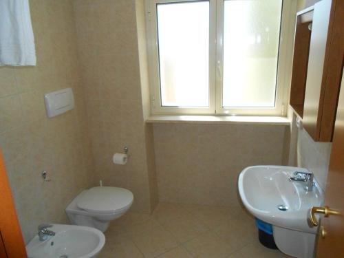 a bathroom with a toilet and a sink and a window at Sacro Cuore Opera Don Guanella in Torre Canne