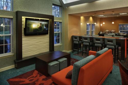 a bar with a tv on a wall and chairs at Residence Inn Mystic Groton in Mystic