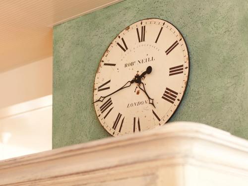 a clock on a green wall with roman numerals at Hotel & Restaurant zum Beck in Stansstad