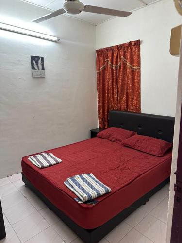 1 dormitorio con 1 cama roja y 2 toallas en Stay Padang Rengas en Padang Rengas