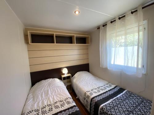- 2 lits dans une petite chambre avec fenêtre dans l'établissement Mobil-Home Fouras, 3 pièces, 4 personnes - FR-1-709-61, à Fouras