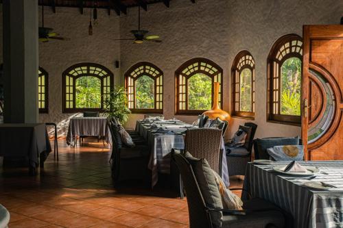 una sala da pranzo con tavoli, sedie e finestre di SCP Corcovado Wilderness Lodge a San Pedrillo