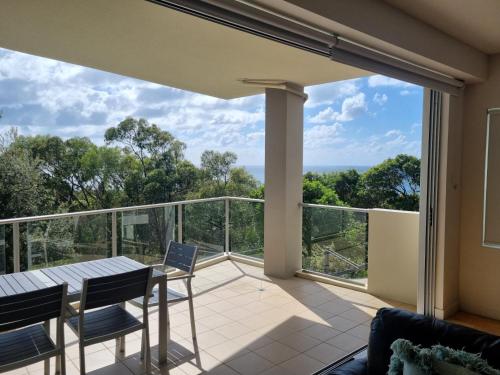 a room with a balcony with a table and chairs at Rainbow Ocean Palms Resort in Rainbow Beach