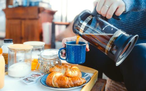 a person pouring coffee into a cup with pastries on a table at Mansfield Glamping - ADULTS ONLY in Mansfield