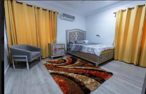 1 dormitorio con 1 cama, 1 silla y 1 alfombra en Cozy homes Accra,Ghana en Owuraman