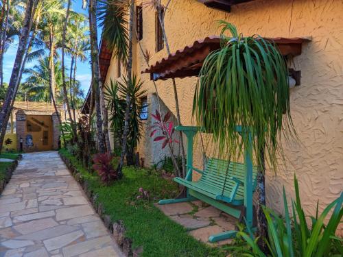 a green bench sitting outside of a house at Villa'l Mare Hotel in Maresias
