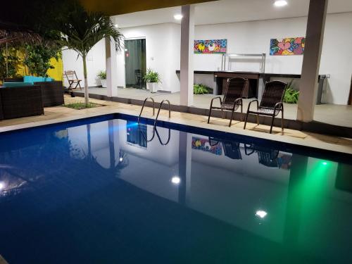 a swimming pool with two chairs and a table at pousada Amarante praia 1 in São Miguel do Gostoso