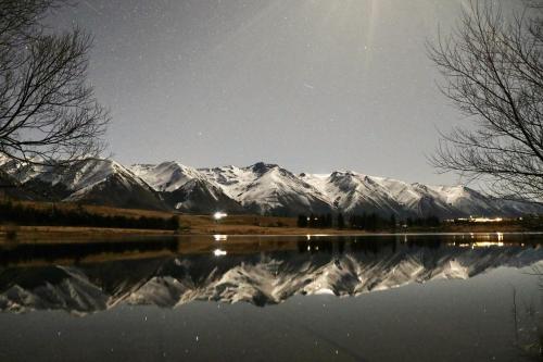 a reflection of snow capped mountains in a lake at night at The Barn at Killin B&B in Ohau