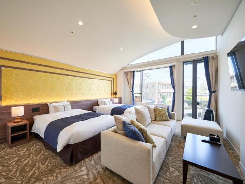 鎌倉市にあるWeBase KAMAKURAのベッド2台とソファが備わるホテルルームです。