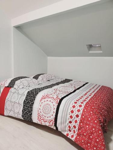 - un lit avec une couette rouge et blanche dans l'établissement Cosy appartement Pierrefitte sur seine proche Paris "Appart'1", à Pierrefitte-sur-Seine