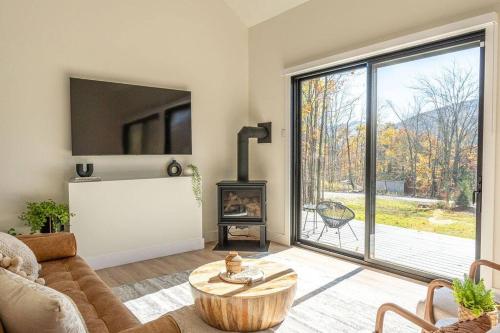 a living room with a couch and a table and a fireplace at Lux Modern Barnhouse Cabin at Hunter Mountain in Hunter