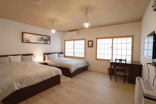 a bedroom with two beds and a desk and windows at Kyo KOZO Kitano Tenjin - Vacation STAY 89906 in Kyoto