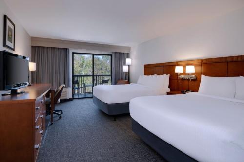 a hotel room with two beds and a flat screen tv at Courtyard Tampa North / I-75 Fletcher in Tampa