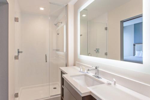 a white bathroom with a sink and a shower at SpringHill Suites by Marriott Huntington Beach Orange County in Huntington Beach