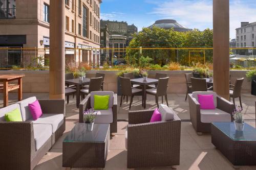 a patio with tables and chairs with colorful pillows at Sheraton Grand Hotel & Spa in Edinburgh