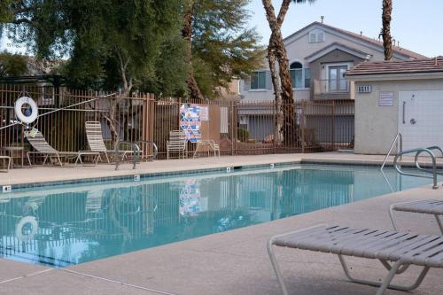 een zwembad met stoelen en een hek en een huis bij Gorgeous home away from home in Las Vegas