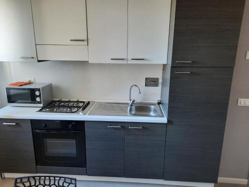 a kitchen with white cabinets and a sink and a stove at Siore Marie gli alloggi in San Giórgio di Nogaro