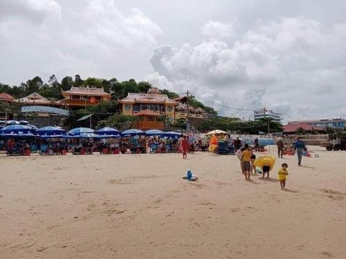 a group of people on a beach with blue umbrellas at Nguyễn Kim Motel in Long Hai